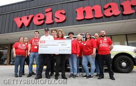 Chief Larry Weikert accepts a ceremonial check for $500 in store credit to Weis Markets. Photo by Darryl Wheeler, Gettysburg Times (used by permission).