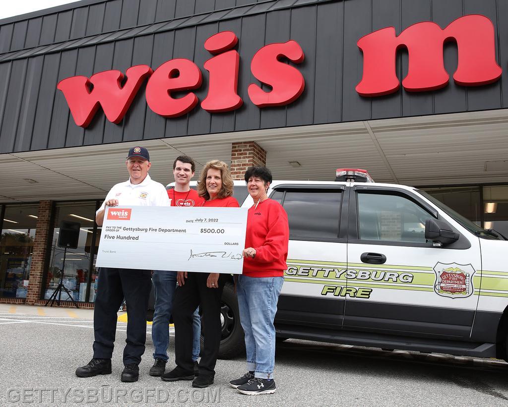 Chief Larry Weikert accepts a ceremonial check for $500 in store credit to Weis Markets. Photo by Darryl Wheeler, Gettysburg Times (used by permission).
